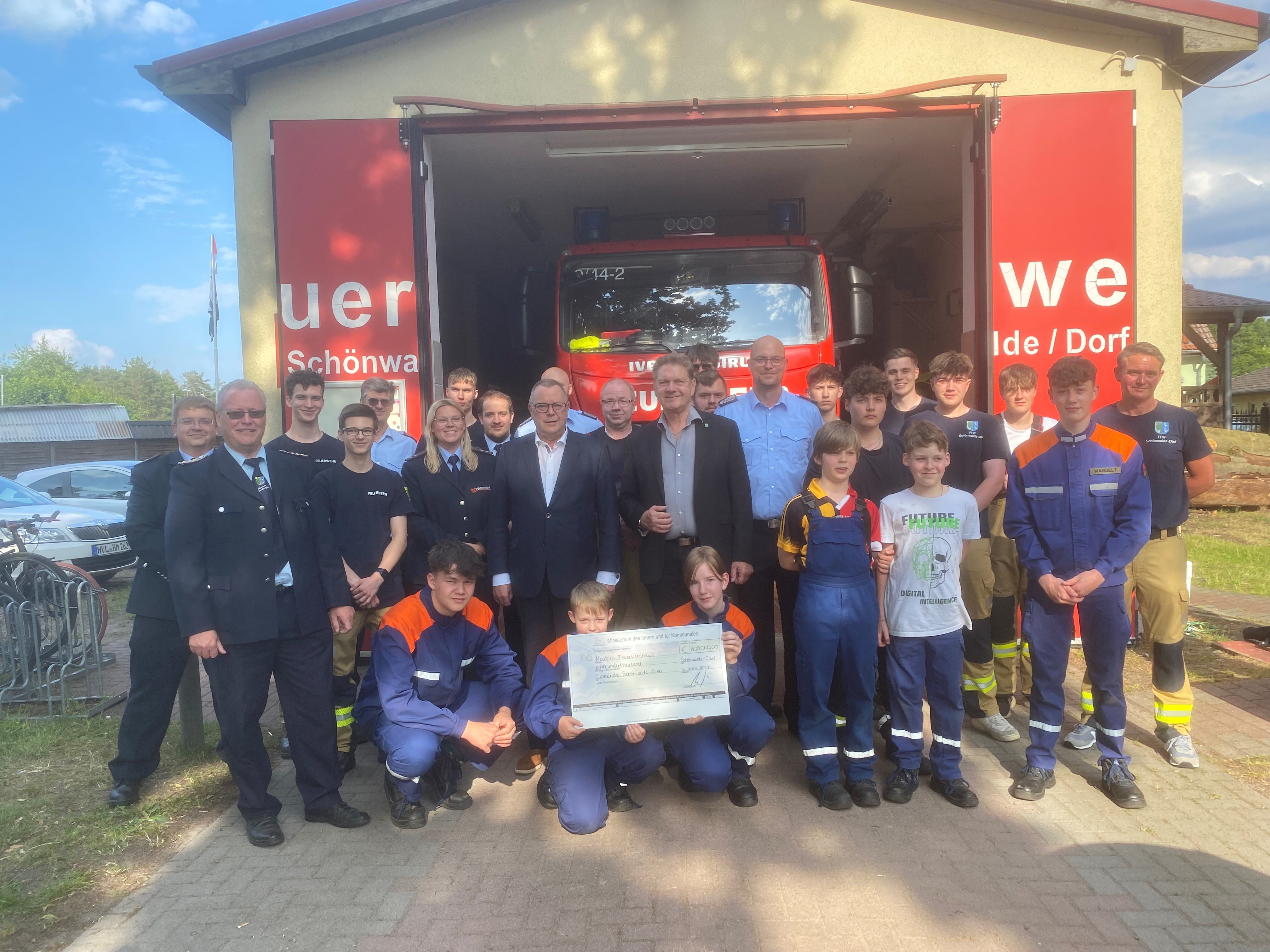 Scheckübergabe vor dem jetzigen Feuerwehrdepot im Ortsteil Schönwalde-Dorf. Innenminister Michael Stübken und Bodo Oehme zusammen mit den Kammeraden und der Jugendfeuerwehr.